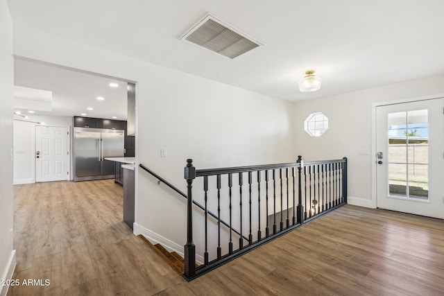 corridor with light wood-style flooring, recessed lighting, an upstairs landing, visible vents, and baseboards