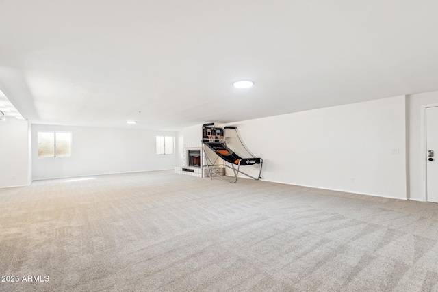 below grade area with carpet floors, a brick fireplace, and baseboards