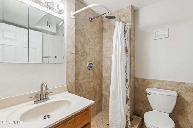 bathroom with a stall shower, visible vents, toilet, vanity, and tile walls