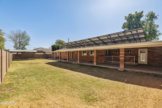 back of house featuring a patio area, a fenced backyard, a yard, and brick siding