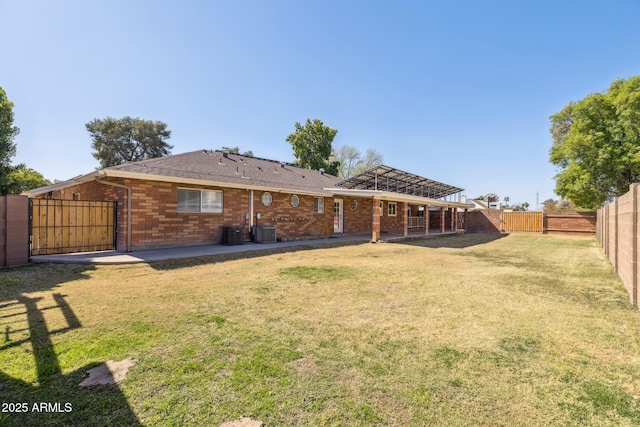 back of property with brick siding, a lawn, cooling unit, and a fenced backyard