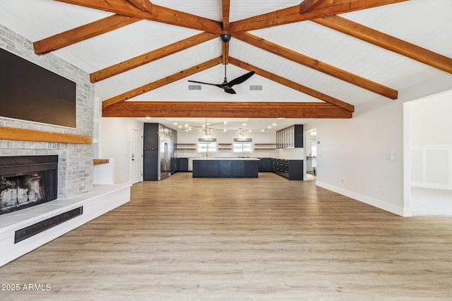 unfurnished living room featuring beam ceiling, a fireplace, light wood-style flooring, and a ceiling fan