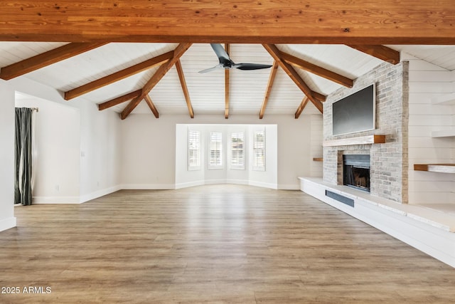 unfurnished living room with vaulted ceiling with beams, light wood-type flooring, a brick fireplace, and a ceiling fan