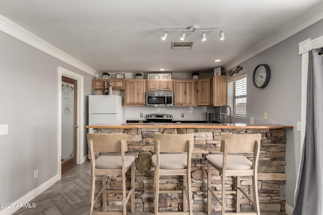 23332 N Serenity Trl, Florence, AZ 85132 - kitchen with stainless steel microwave, electric stove, freestanding refrigerator, crown molding, and a kitchen bar
