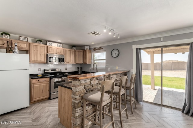 23332 N Serenity Trl, Florence, AZ 85132 - kitchen with appliances with stainless steel finishes, dark countertops, ornamental molding, a kitchen bar, and backsplash