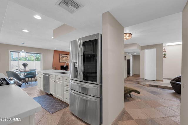 kitchen featuring light countertops, white cabinets, visible vents, stainless steel appliances, and a sink