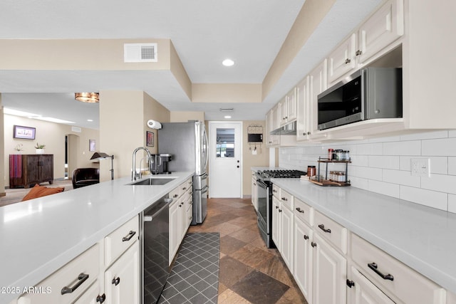 kitchen with tasteful backsplash, light countertops, visible vents, appliances with stainless steel finishes, and a sink