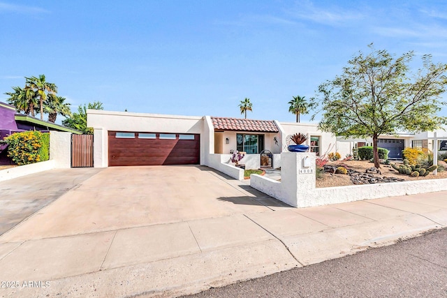 view of front of home with a tiled roof, stucco siding, fence, an attached garage, and driveway
