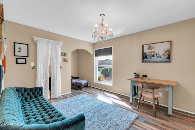 living area featuring a chandelier, arched walkways, baseboards, and wood finished floors