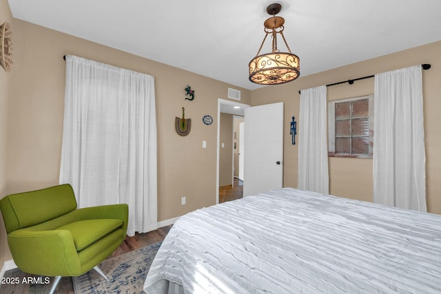 bedroom featuring wood finished floors, baseboards, and visible vents