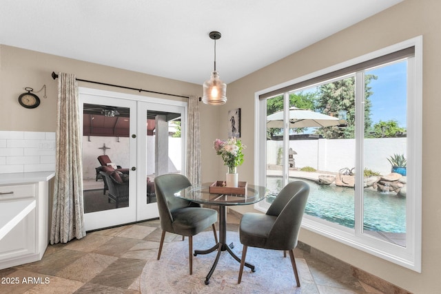 dining area featuring french doors, stone finish flooring, and a healthy amount of sunlight