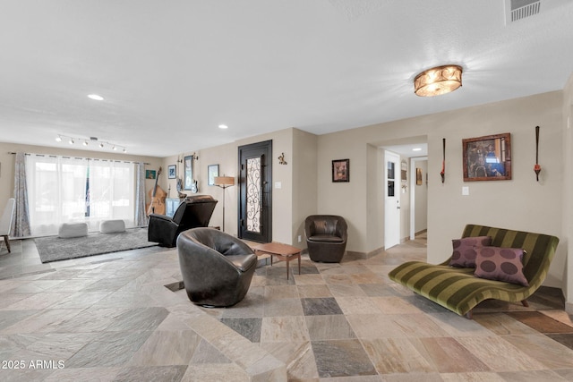living area with stone finish flooring, baseboards, visible vents, and recessed lighting