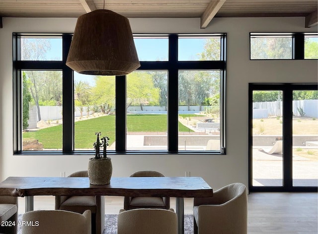 unfurnished dining area featuring beam ceiling, wood-type flooring, wooden ceiling, and a wealth of natural light