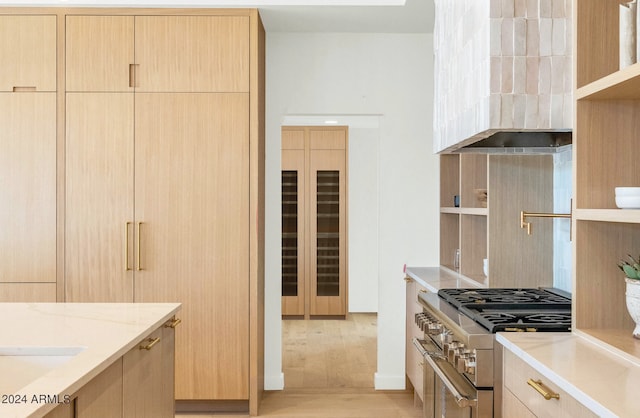 kitchen featuring light stone countertops, light brown cabinets, stainless steel stove, and light hardwood / wood-style flooring