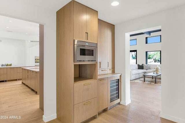 kitchen with light hardwood / wood-style flooring, oven, and light brown cabinets