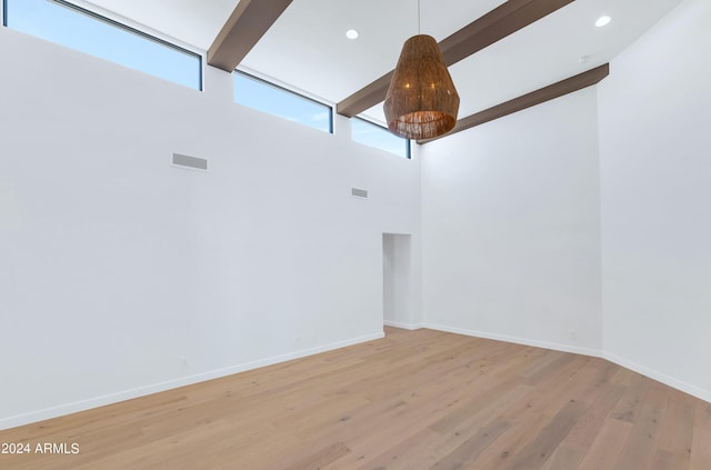 spare room featuring beamed ceiling, high vaulted ceiling, hardwood / wood-style floors, and an inviting chandelier