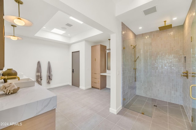 bathroom with tile patterned floors, vanity, a shower with shower door, and a tray ceiling