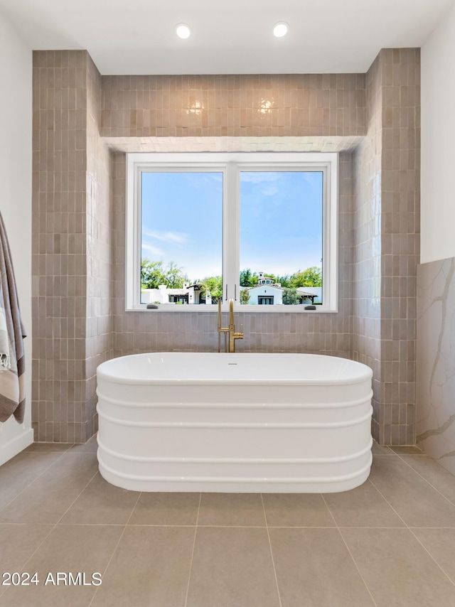 bathroom with tile patterned flooring, tile walls, and a washtub