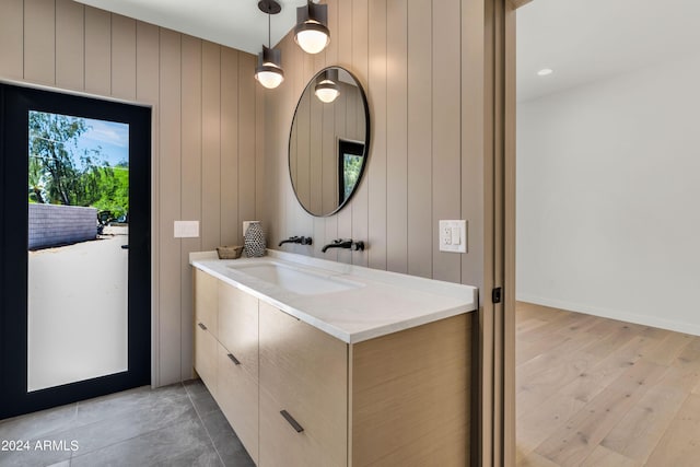 bathroom with hardwood / wood-style floors, vanity, and wood walls