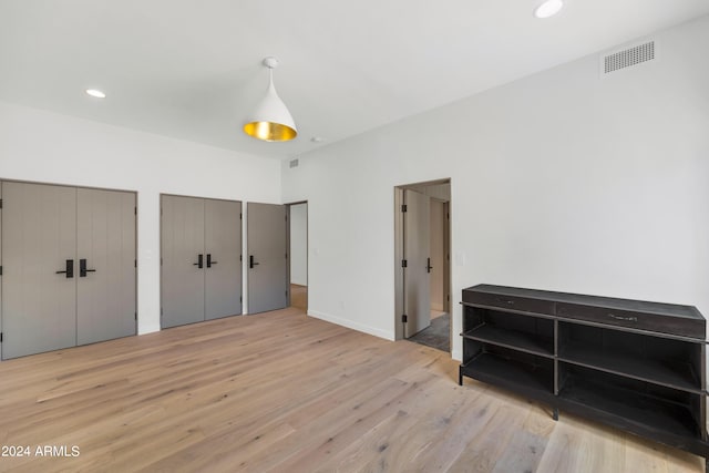 bedroom with light wood-type flooring and multiple closets