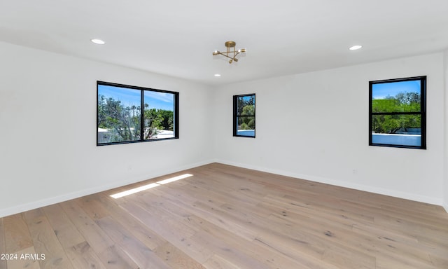 spare room featuring light wood-type flooring and a notable chandelier