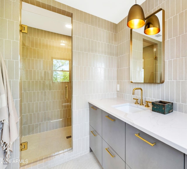 bathroom with tile patterned floors, vanity, tile walls, and walk in shower