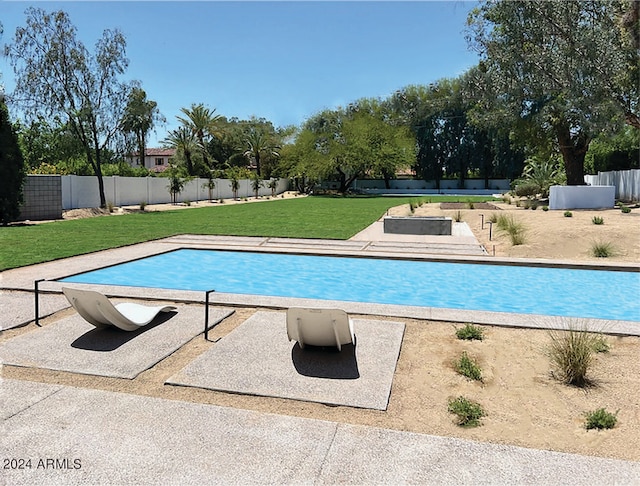 view of swimming pool with a yard