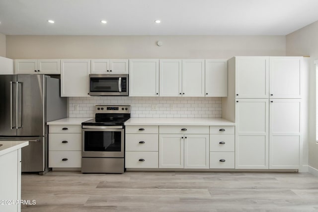 kitchen featuring stainless steel appliances, white cabinetry, backsplash, and light hardwood / wood-style floors