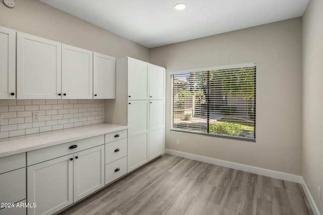 interior space featuring light hardwood / wood-style flooring, white cabinets, and decorative backsplash