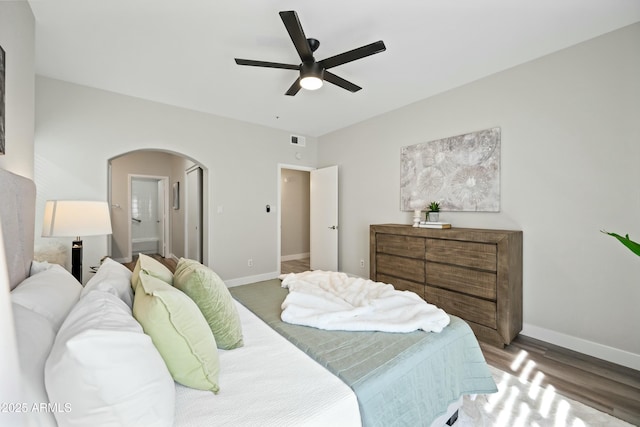 bedroom featuring dark wood-type flooring, ensuite bath, and ceiling fan