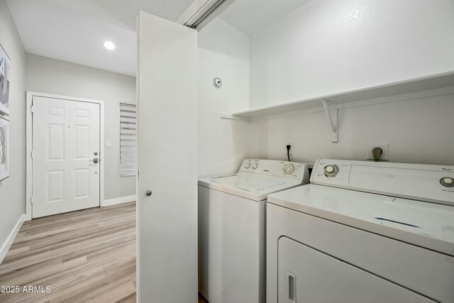 laundry area featuring washing machine and clothes dryer and light wood-type flooring