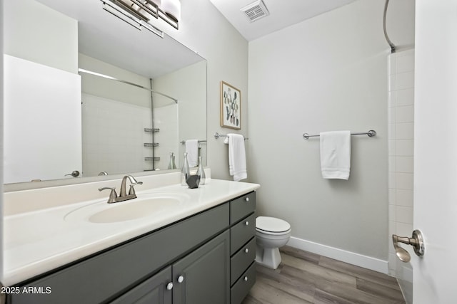 bathroom featuring vanity, toilet, wood-type flooring, and a shower