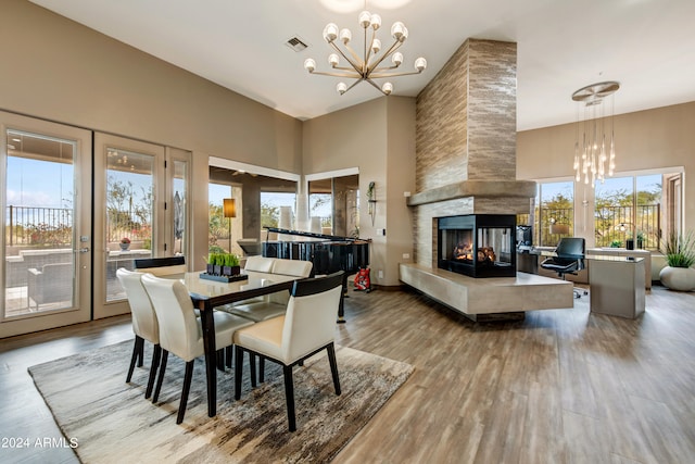 dining room with light wood-type flooring, an inviting chandelier, and a multi sided fireplace