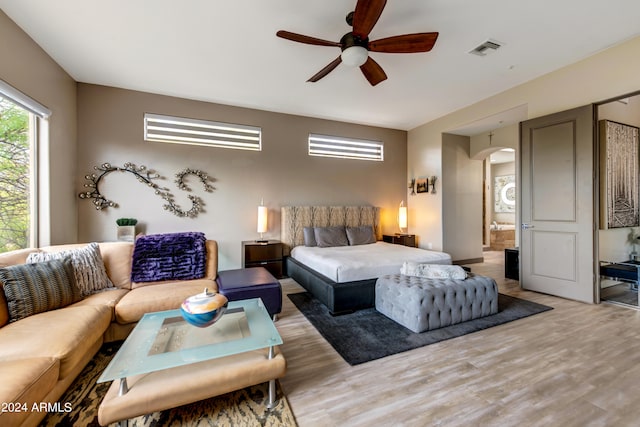 bedroom featuring ensuite bath, light hardwood / wood-style flooring, and ceiling fan