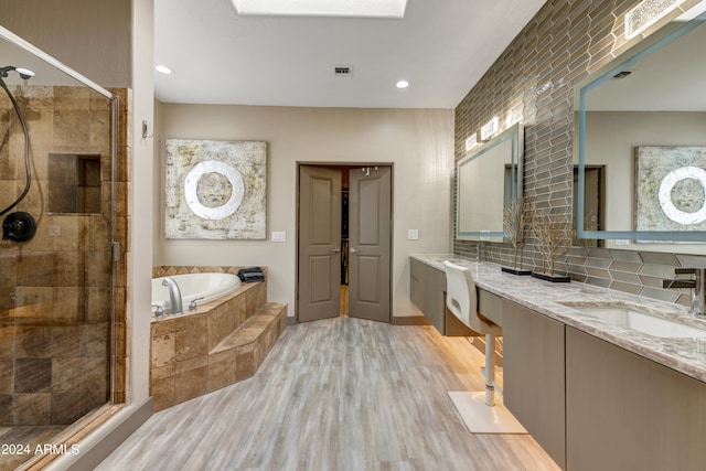 bathroom with large vanity, tasteful backsplash, hardwood / wood-style flooring, plus walk in shower, and dual sinks