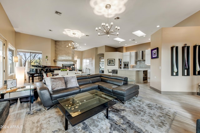 living room featuring light hardwood / wood-style flooring, a fireplace, and a notable chandelier