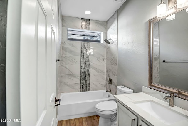 full bathroom with toilet, tiled shower / bath, vanity, and hardwood / wood-style floors