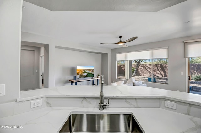 kitchen featuring light stone countertops, sink, and ceiling fan