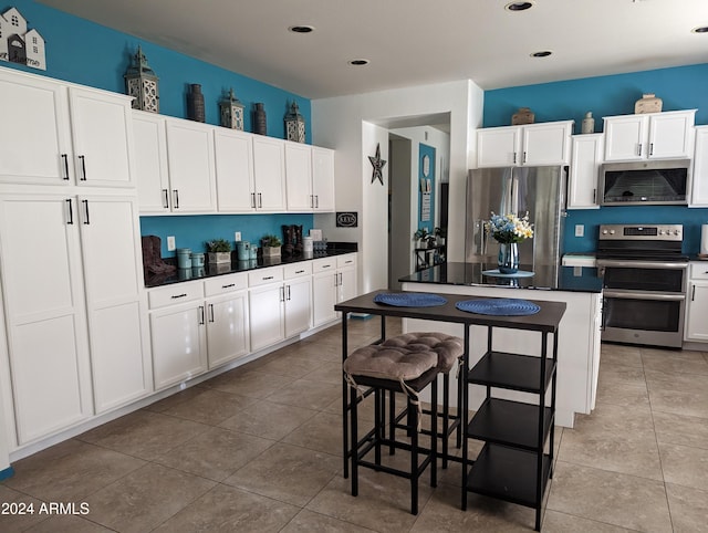 kitchen featuring a breakfast bar area, appliances with stainless steel finishes, tile patterned floors, and white cabinets