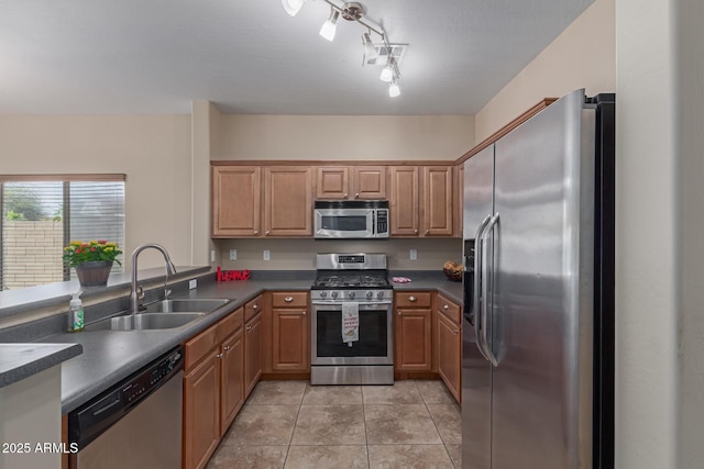 kitchen featuring appliances with stainless steel finishes, dark countertops, light tile patterned flooring, and a sink