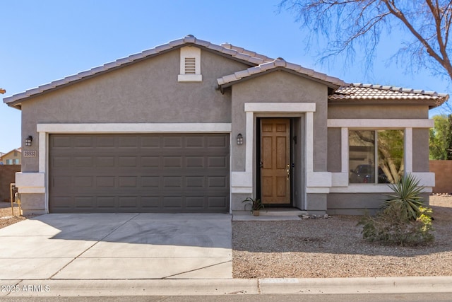 view of front of property with concrete driveway, a tiled roof, an attached garage, and stucco siding