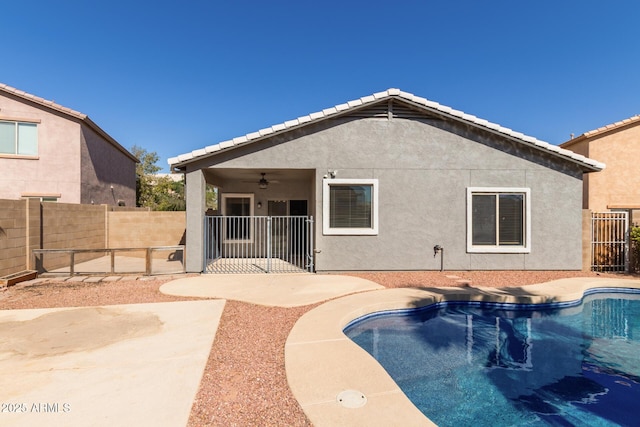 rear view of property featuring a patio, a fenced backyard, a ceiling fan, a fenced in pool, and stucco siding