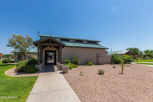 view of front of house with metal roof, a front lawn, and stucco siding