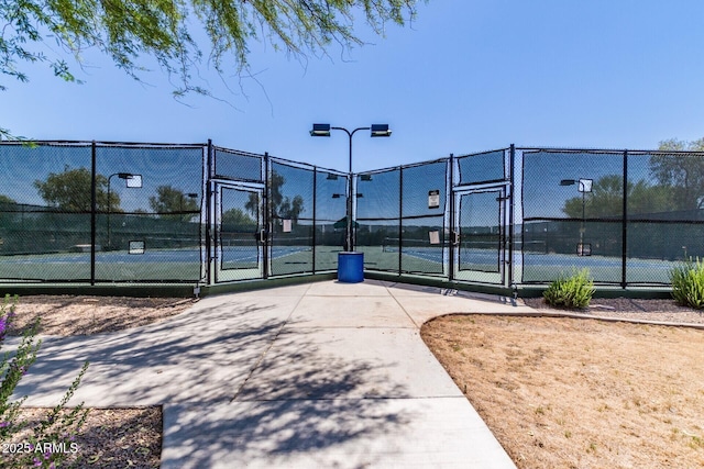 view of tennis court featuring a gate and fence