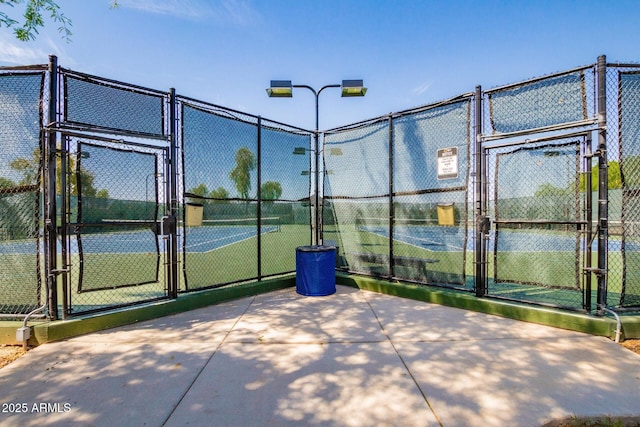 view of tennis court with a gate and fence