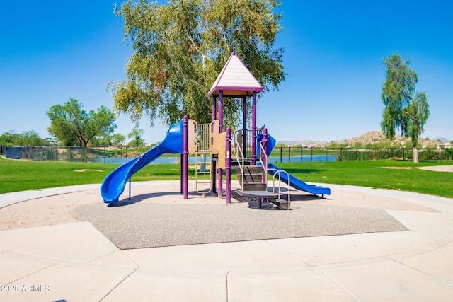 community jungle gym with a water view, fence, and a yard