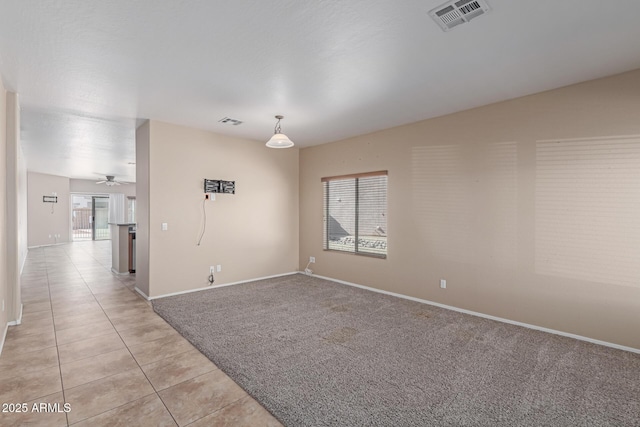 empty room with light carpet, light tile patterned floors, baseboards, and visible vents