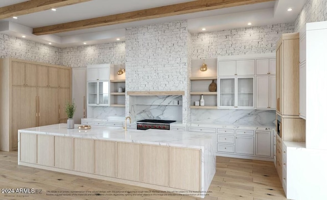 kitchen featuring light stone counters, beamed ceiling, stainless steel stove, a spacious island, and light wood-type flooring