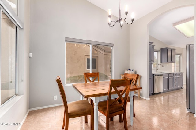 tiled dining room with sink, a healthy amount of sunlight, vaulted ceiling, and a notable chandelier