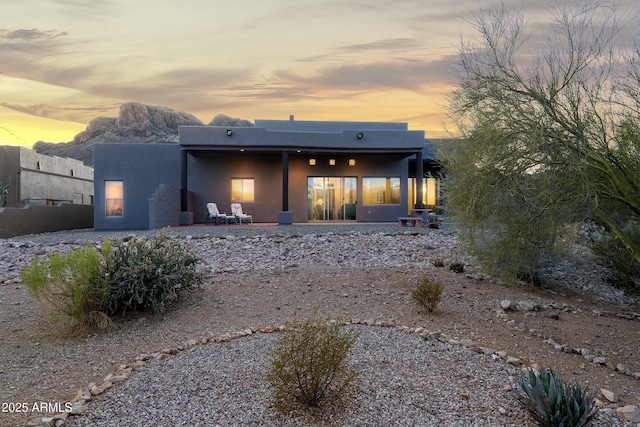 back house at dusk with a patio area